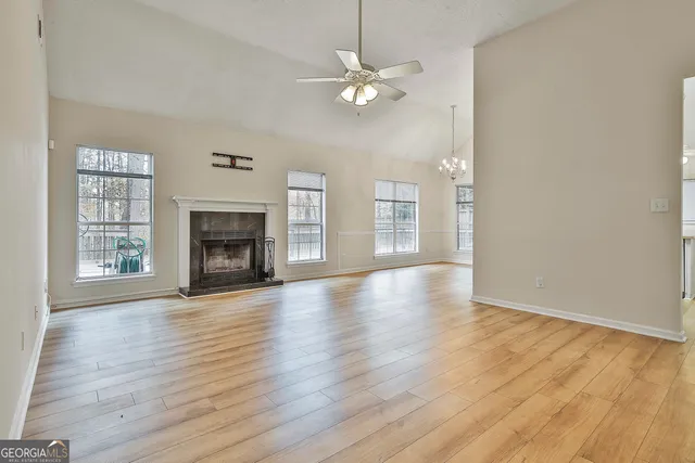 an empty room with wooden floor fireplace and windows