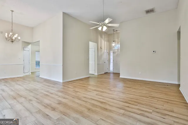 an empty room with wooden floor and stainless steel appliances