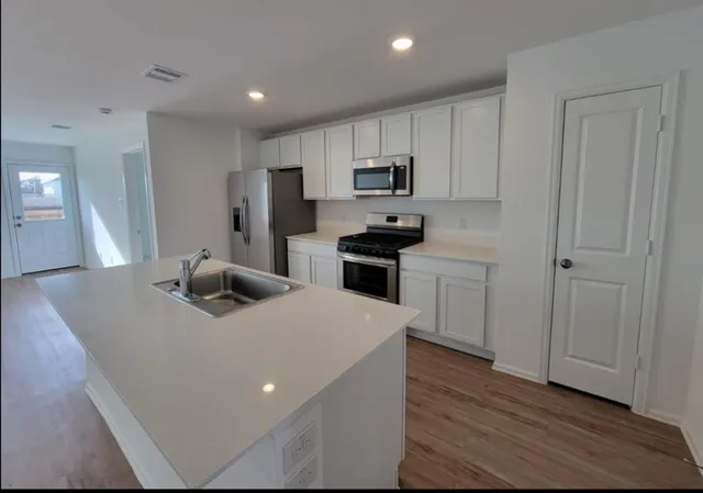 a kitchen with stainless steel appliances a sink a stove a refrigerator cabinets and a counter top space