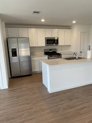 a kitchen with stainless steel appliances a refrigerator a sink a stove a microwave and cabinets