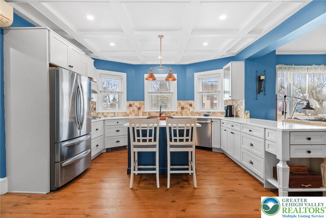 4303 Newburg Road Bethlehem, PA 18020 - Photo 11 of 63 a kitchen with stainless steel appliances kitchen island granite countertop a refrigerator a stove a dining table and chairs with wooden floor