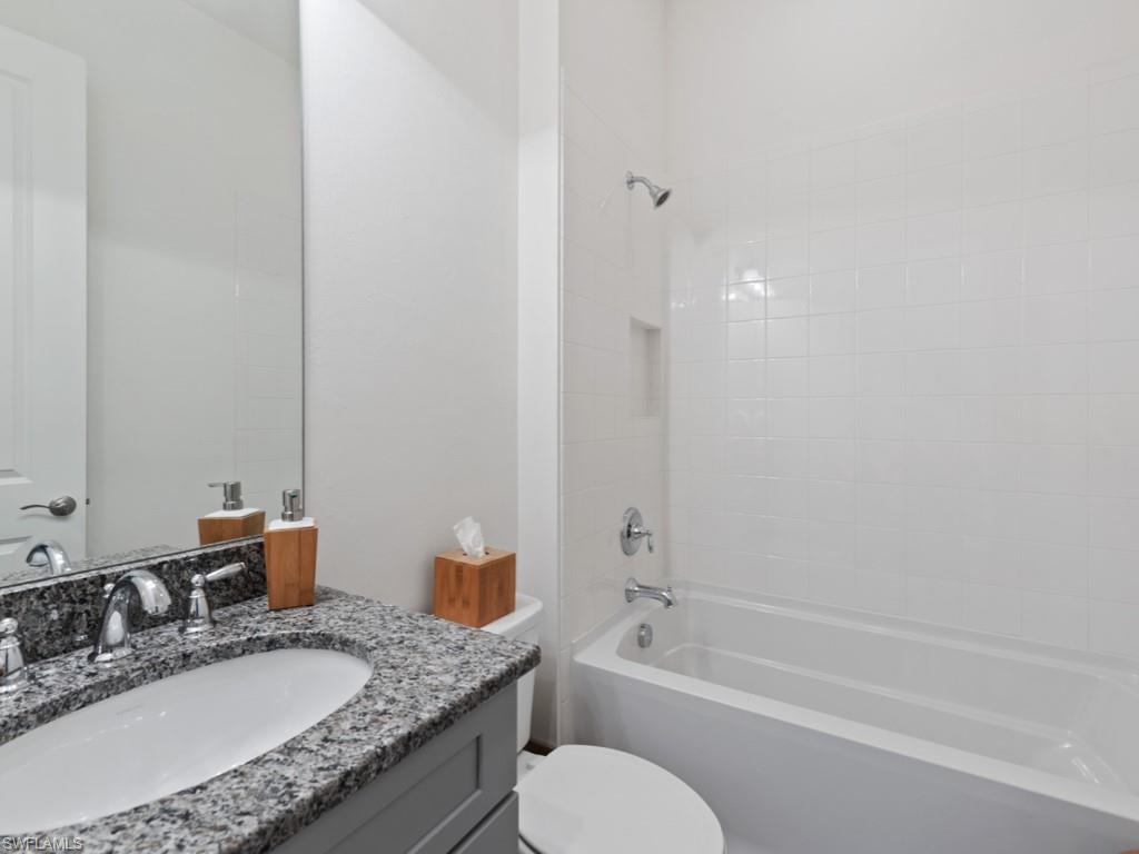 10191 Coconut Road Estero, FL 34135 - Photo 7 of 14 a bathroom with a granite countertop sink mirror toilet and bathtub