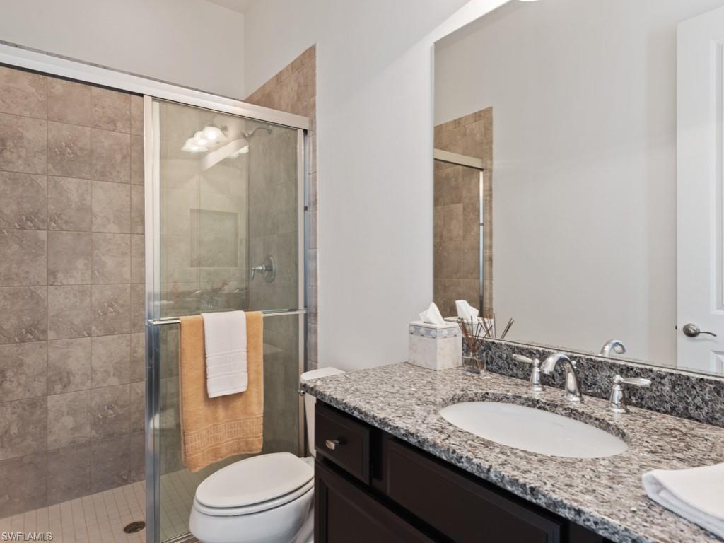 10191 Coconut Road Estero, FL 34135 - Photo 9 of 14 a bathroom with a granite countertop sink toilet a mirror and shower