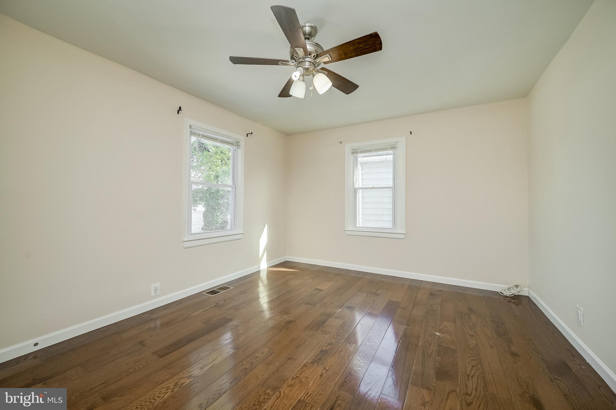 816 Maple Avenue Laurel, MD 20707 - Photo 26 of 45 an empty room with wooden floor ceiling fan and windows