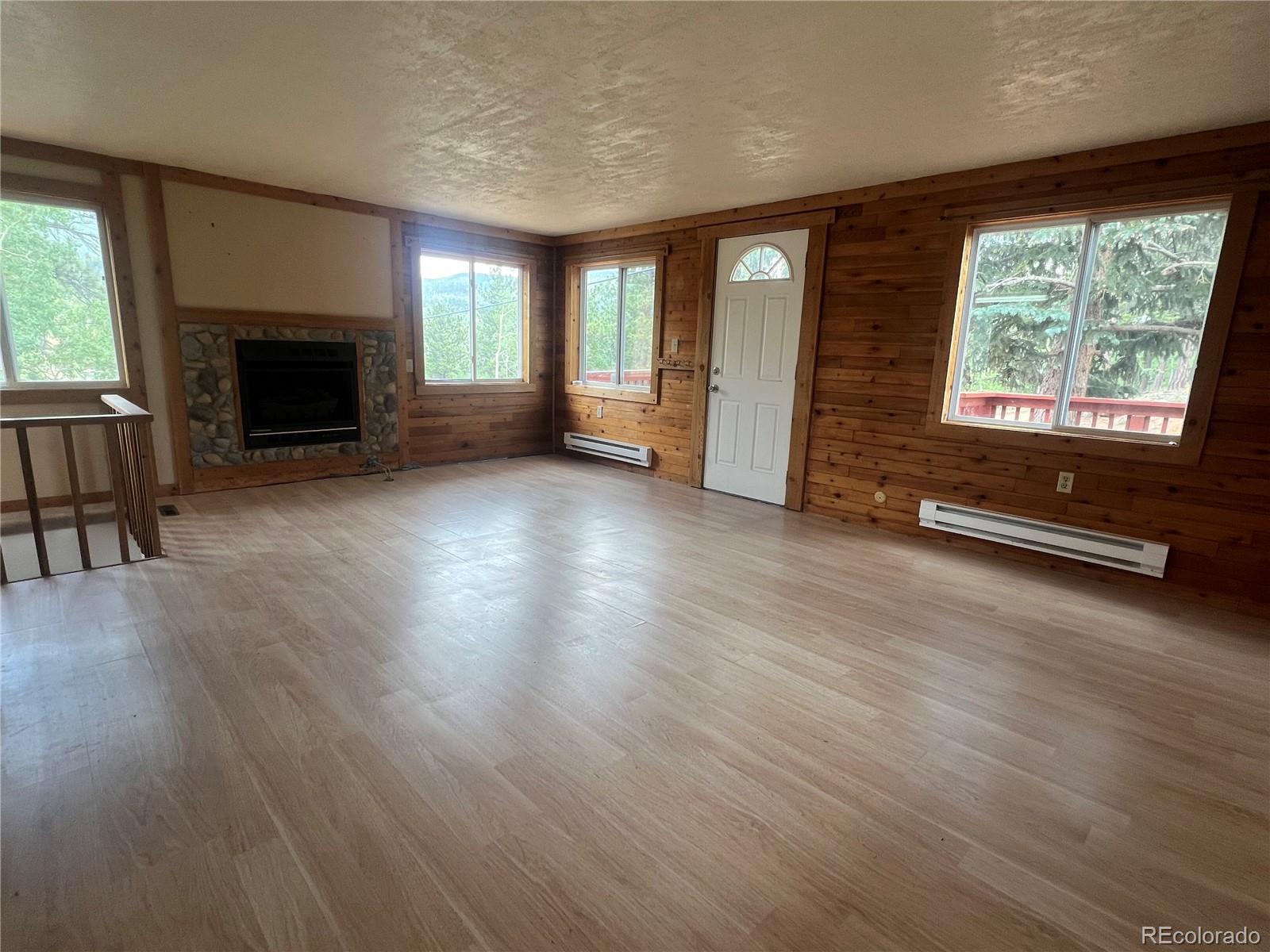 95 Appleby Street Bailey, CO 80421 - Photo 3 of 36 an empty room with windows a fireplace and wooden floor