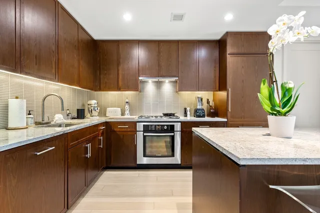 a kitchen with kitchen island granite countertop stainless steel appliances lots of counter top space cabinets and a sink