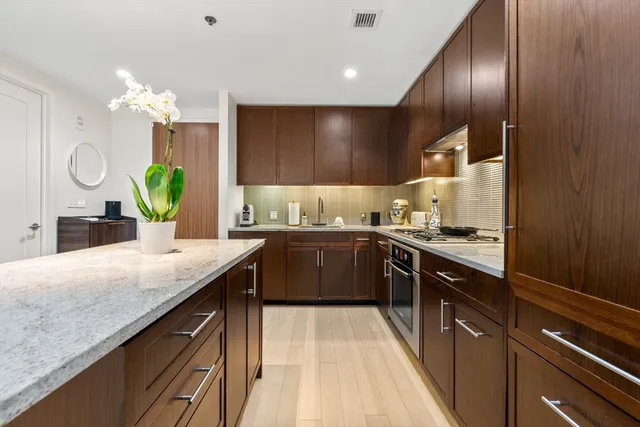 a kitchen with kitchen island granite countertop a sink a counter top space cabinets and stainless steel appliances