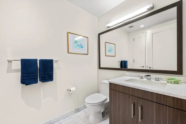 a bathroom with a sink vanity mirror and toilet