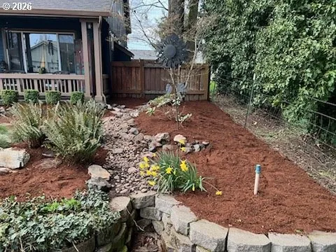 a view of a yard with plants and wooden fence