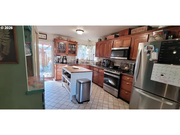 a kitchen with stainless steel appliances kitchen island granite countertop a refrigerator and a stove top oven