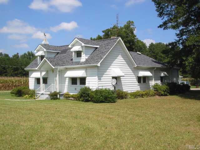 a front view of house with yard and trees in the background
