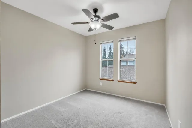 an empty room with a window and a ceiling fan