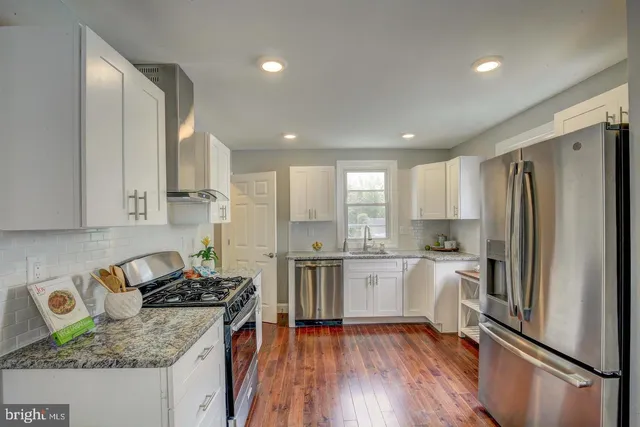 a kitchen with a refrigerator a stove a sink and white cabinets