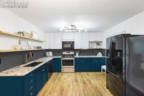 a kitchen with kitchen island granite countertop a sink refrigerator and cabinets