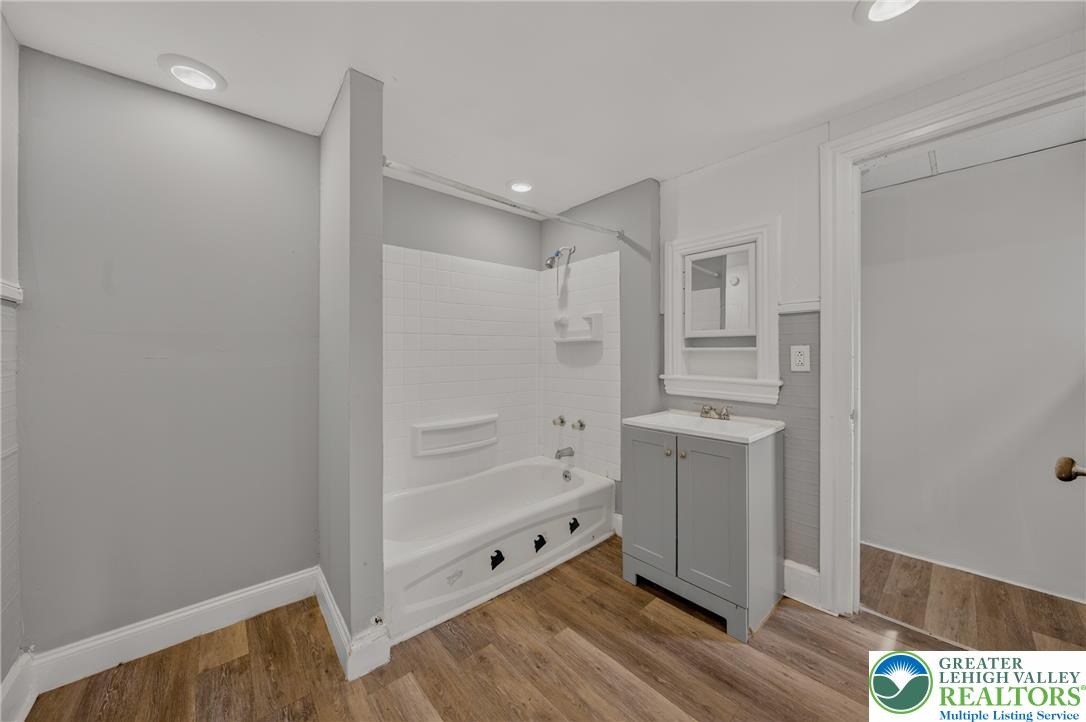 313 Main Street Slatington, PA 18080 - Photo 42 of 73 A well-appointed bathroom features a combined shower and tub, with a stylish vanity and vanity mirror, all complemented by resilient wood flooring.
