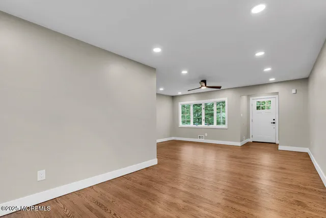 an empty room with wooden floor and windows