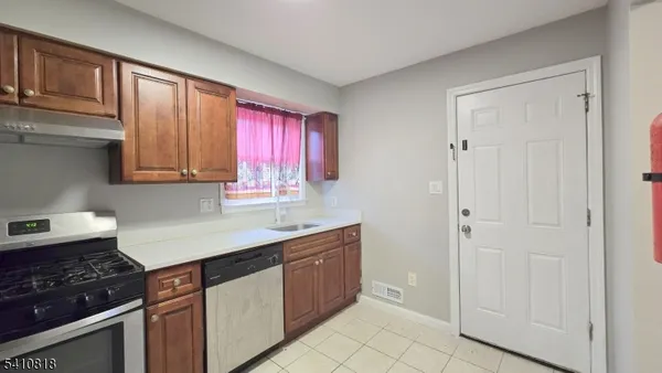 a kitchen with stainless steel appliances granite countertop a stove a sink and a refrigerator with wooden cabinets