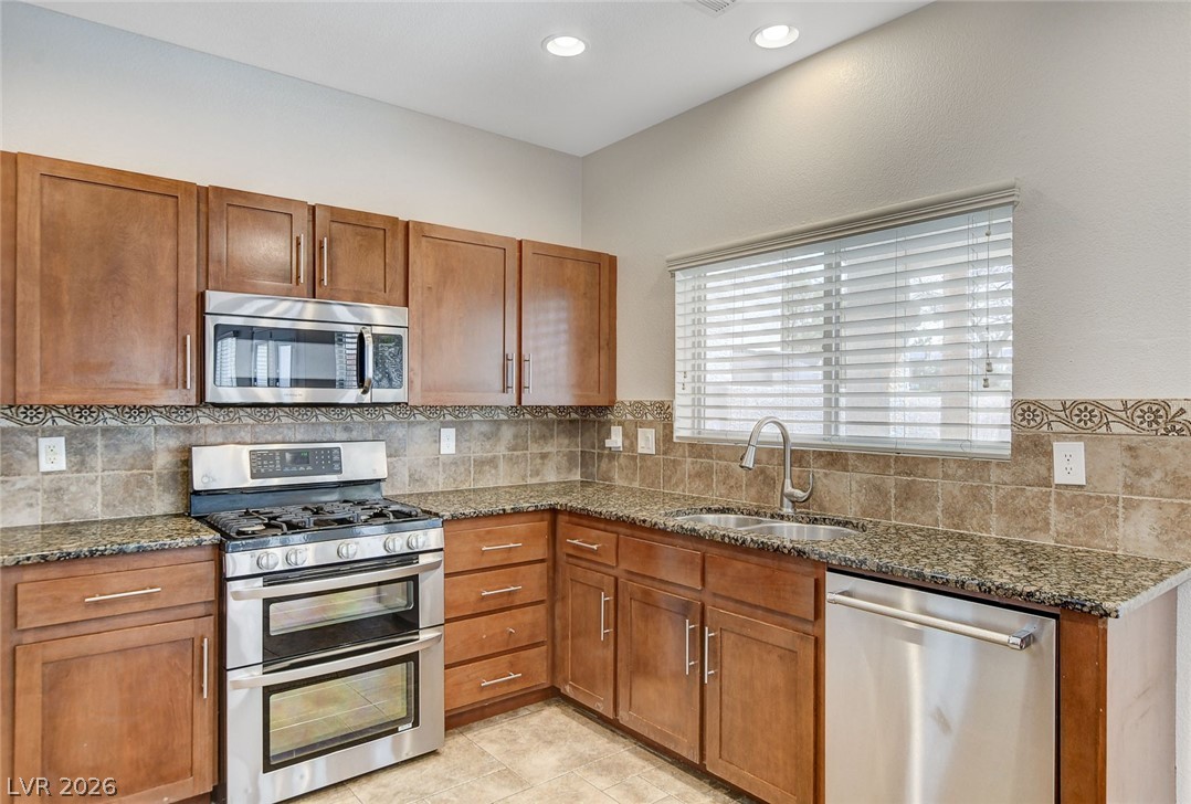 191 Verde Ridge Court Henderson, NV 89012 - Photo 14 of 36 Kitchen featuring appliances with stainless steel finishes, a sink, dark stone countertops, backsplash, and recessed lighting
