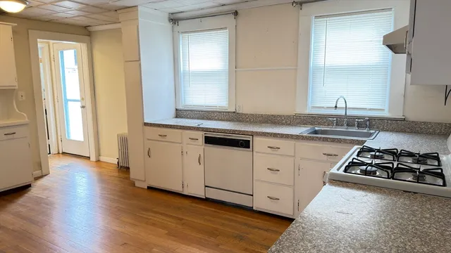 a kitchen with granite countertop a stove and a wooden floor