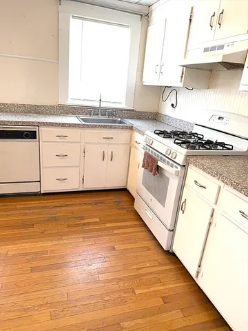 a view of a kitchen with stainless steel appliances granite countertop a stove a sink and white cabinets