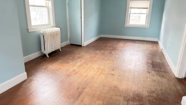 an empty room with wooden floor and windows