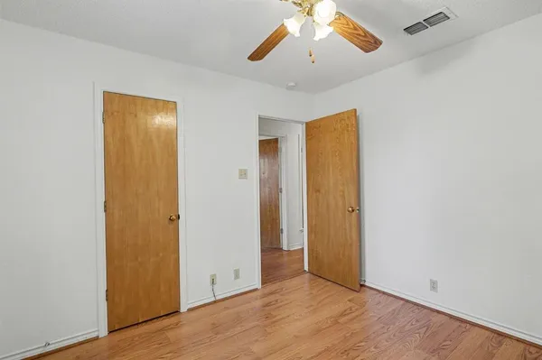 an empty room with wooden floor and hallway