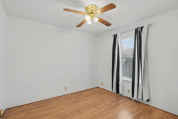 an empty room with a window and a fan