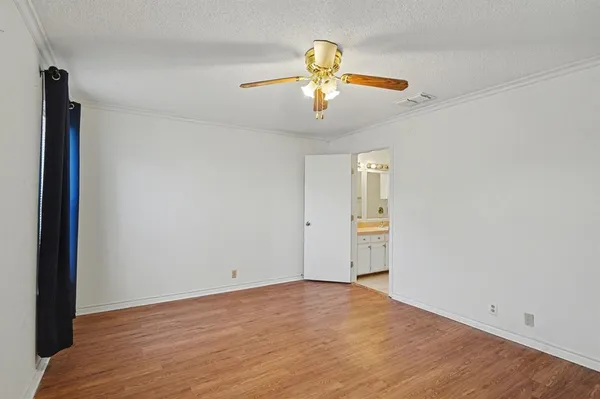 an empty room with a chandelier fan and wooden floor