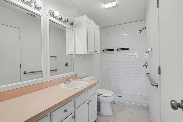 a bathroom with a granite countertop sink a toilet and shower