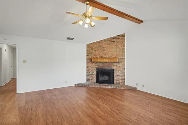 an empty room with a fireplace and wooden floor