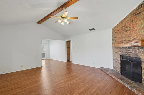 a view of an empty room with wooden floor and a fireplace