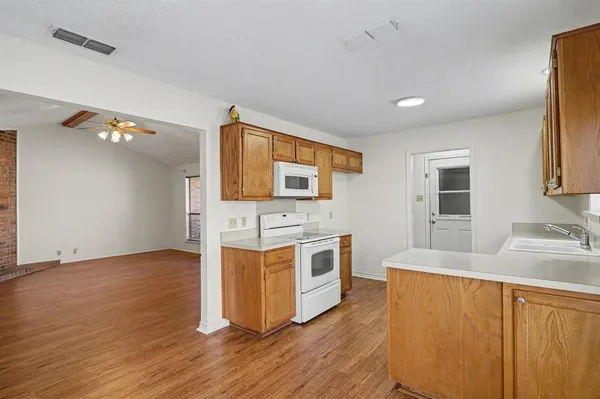 a kitchen with stainless steel appliances granite countertop a stove a sink and a refrigerator with wooden floors
