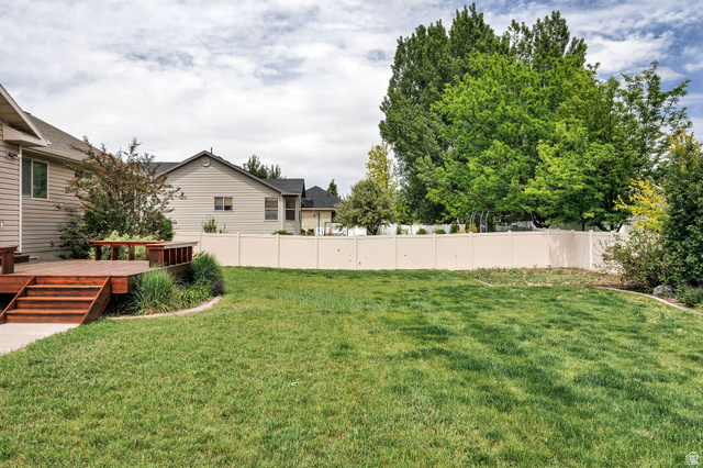 2912 South 1080th Street West Logan, UT 84321 - Photo 39 of 43 Expansive grassy yard with a multi-level wood deck, built-in benches, and a privacy fence