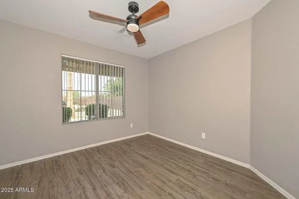 an empty room with wooden floor fan and windows