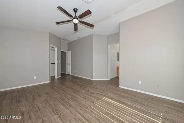an empty room with wooden floor and ceiling fan