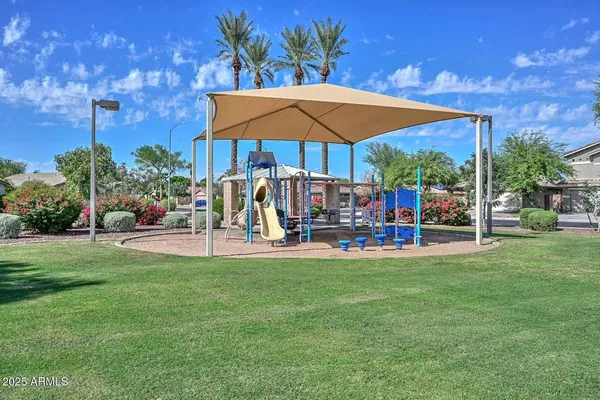 a view of a table and chairs under an umbrella in front of house