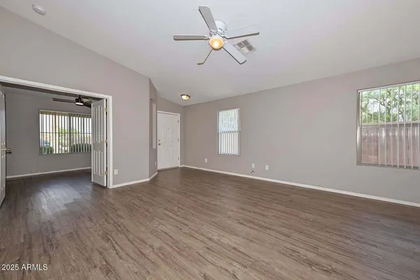 an empty room with wooden floor fan and windows