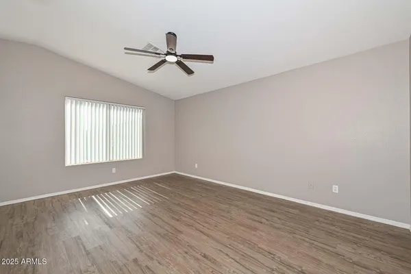 a view of empty room with wooden floor and fan