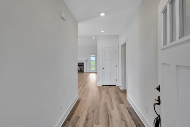 a view of an empty room with wooden floor fireplace and a window