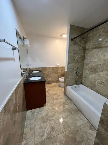 a bathroom with a granite countertop sink a toilet and shower