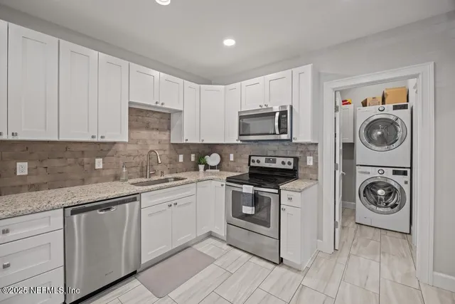 a kitchen with granite countertop white cabinets and stainless steel appliances