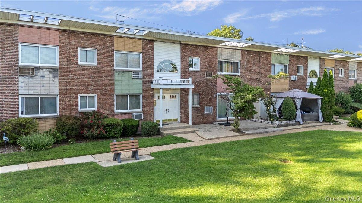 267 North Newbridge Road, Unit 2D Levittown, NY 11756 - Photo 1 of 22 Brick facade apartment building featuring a portico entry with double doors and an arched window