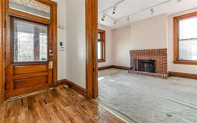 a view of an empty room with wooden floor fireplace and a window
