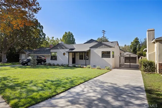 a front view of a house with a garden and trees