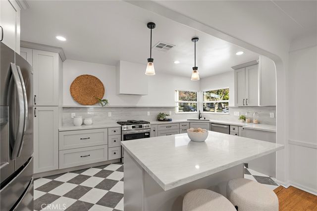 a kitchen with stainless steel appliances a refrigerator a sink a stove a table and chairs