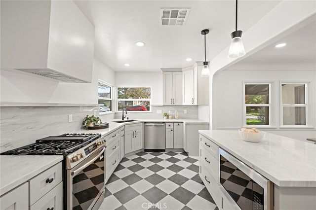 a kitchen with stainless steel appliances granite countertop a sink a stove and a wooden cabinets