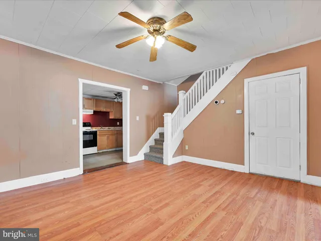 an empty room with wooden floor chandelier and windows