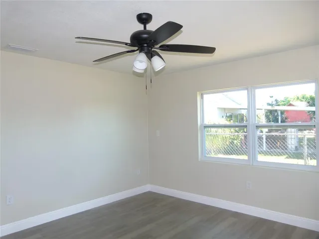 an empty room with a window and a fan