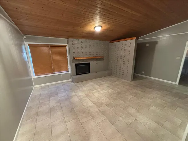 a view of an empty room with a fireplace and a window