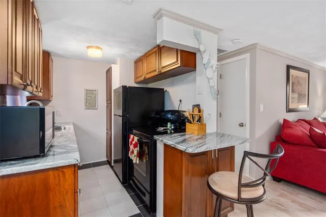 a kitchen with stainless steel appliances granite countertop a table chairs and a refrigerator